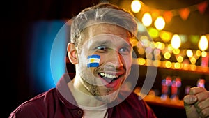 Soccer fan with argentinian flag painted on cheek happy team winning competition