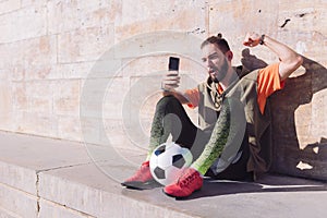Soccer fan celebrates victory consulting phone