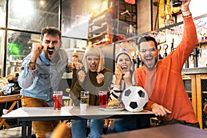 Soccer fans celebrating while watching soccer match on TV in bar