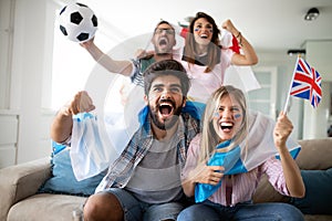 Soccer fans emotionally watching game in the living room.