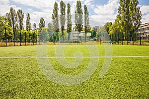 Soccer field with artificial green grass near the school. Amateur football field. Sunny summer day