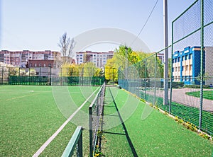 Soccer field with artificial green grass near the school. Amateur football field. Sunny summer day