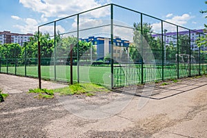 Soccer field with artificial green grass near the school. Amateur football field. Sunny summer day