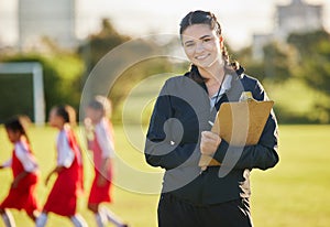 Soccer field, woman coach with and girl team training on grass in background. Sports, youth development and teamwork, a