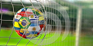 Soccer Football ball with flags of south america countries in net on football stadium. America championship 2021