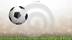 Soccer football ball on green grass field with light blurred bokeh background.