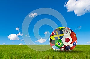 Soccer football with country flags isolated on lush grass and blue sky. World championship