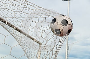 Soccer football in Goal net with the sky field.