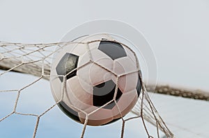 Soccer football in Goal net with the sky field.