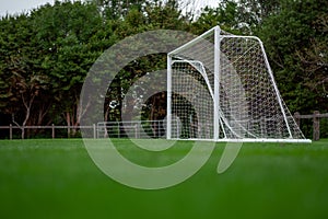 Soccer of football goal posts against dark trees background. Sport equipment. Selective focus. Low angle of view