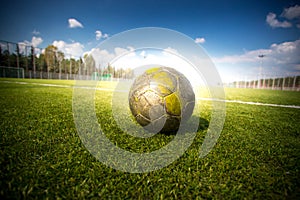 Soccer football on grass field at sun beams