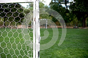 Soccer football net background over green grass and blurry stadium. Background of soccer football goal in stadium on match day