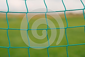 Soccer football net background wallpaper over green grass and blurry stadium behind