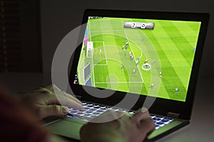 Soccer or football video game in laptop. Young man playing.