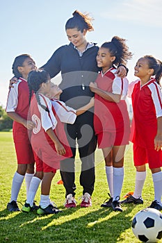 Soccer, girl group hug and coach with happiness, smile or team building, diversity and solidarity on grass pitch. Young