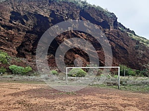 Soccer goal in a dirt area with a volcanic mountain. Sport in marginal urban areas. Football area