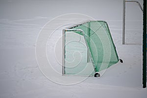 Soccer goal with green netting and pitch under snow in winter