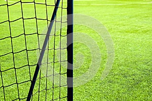 Soccer goal net on green grass field background