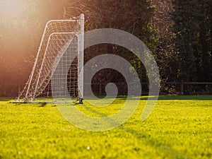 Soccer goal post in a green field, Selective focus, Warm sunny day, Sun flare, dark trees in the background. Concept football