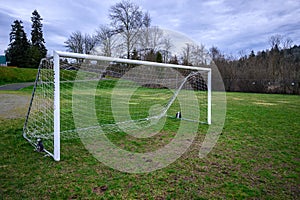 Soccer goal on a wet and worn grass field, stormy sky in the background