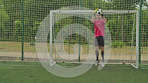 Soccer goalie practicing to defend football goal on pitch outdoors