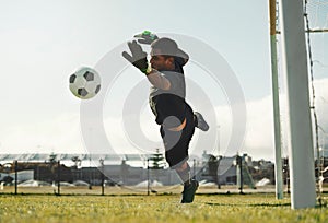 Soccer, goalkeeper and jump, saving ball from goals at outdoor sports field. Football, goalie and competition game with
