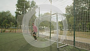 Soccer goalkeeper making diving save on football pitch at daybreak