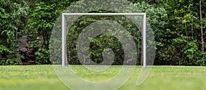 Soccer goalpost on field with forest backdrop..