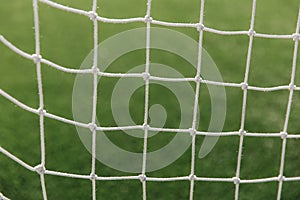 Soccer net background, view from behind the goal with blurred field pitch. Football match
