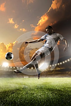 Soccer player in action on sunset stadium background