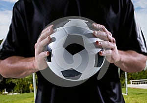 soccer player with ball in his hands, field background