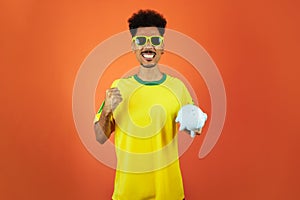 Soccer Player - Black Man Celebrating Holding Pig Coin Isolated on Orange Background
