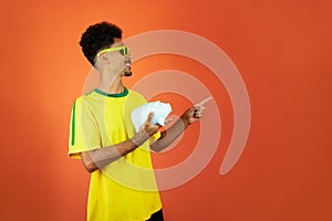 Soccer Player - Black Man Celebrating Holding Pig Coin Isolated on Orange Background