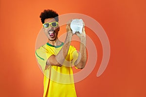 Soccer Player - Black Man Celebrating Holding Pig Coin Isolated on Orange Background