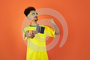 Soccer Player - Black Man Celebrating Holding Solar Photovoltaic Panel Isolated on Orange Background