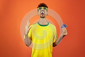 Soccer Player - Black Man Celebrating Holding Solar Photovoltaic Panel Isolated on Orange Background