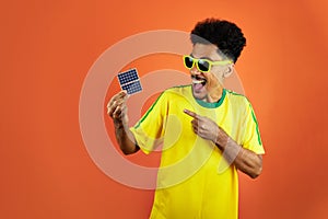 Soccer Player - Black Man Celebrating Holding Solar Photovoltaic Panel Isolated on Orange Background