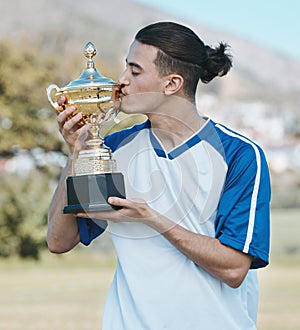 Soccer player, celebrate and competition with trophy in the outdoor with a kiss after win. Sports person, champion and