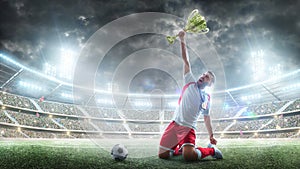 Soccer player celebrates winning the open stadium. Soccer player holds a trophy one hand . Medal on the neck. The winner