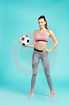 Soccer player. Full length of young beautiful woman in sportswear holding soccer ball and smiling at camera while