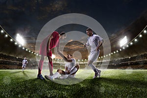 Soccer player helps onother one on sunset stadium background panorama