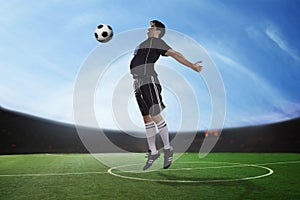 Soccer player hitting the ball with his chest in the stadium, day time