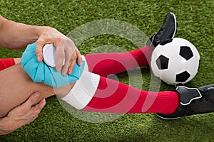 Soccer player icing knee with ice pack