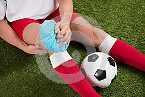 Soccer player icing knee with ice pack