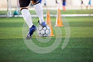 Soccer player jogging and control ball around cone markers for soccer training