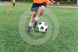 Soccer player kicking ball on field. Soccer players on training session. Close up footballer feet kicking ball on grass.