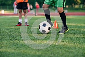 Soccer player kicking ball on field. Soccer players on training session. Close up footballer feet kicking ball on grass.