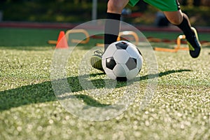 Soccer player kicking ball on field. Soccer players on training session. Close up footballer feet kicking ball on grass.