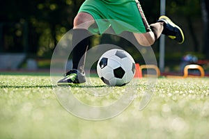 Soccer player kicking ball on field. Soccer players on training session. Close up footballer feet kicking ball on grass.