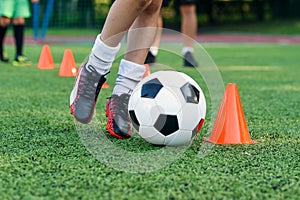 Soccer player kicking ball on field. Soccer players on training session. Close up footballer feet kicking ball on grass.